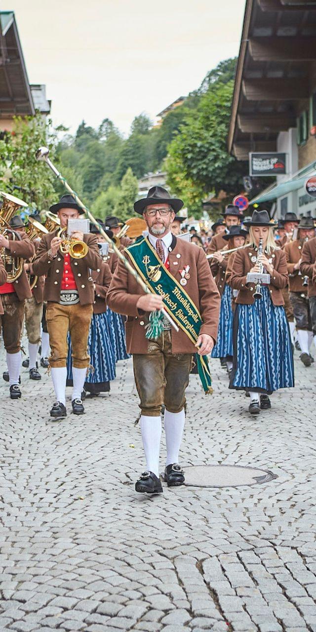 Österreichischer Festumzug mit Musikern in Tracht durch das Dorf Saalbach