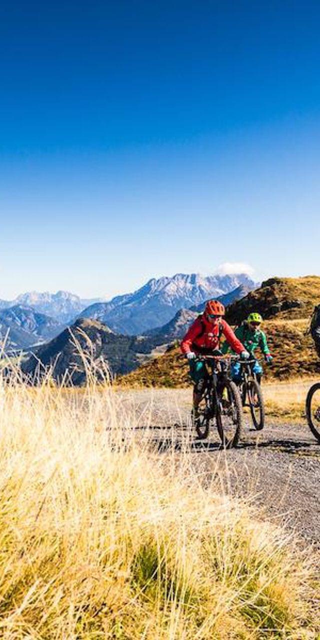 Gruppe von Mountainbikern auf einem Alpinen Trail mit Panoramablick auf die Berge