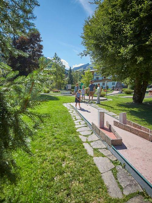 Familie spielt Minigolf an einem sonnigen Tag in einem malerischen Park