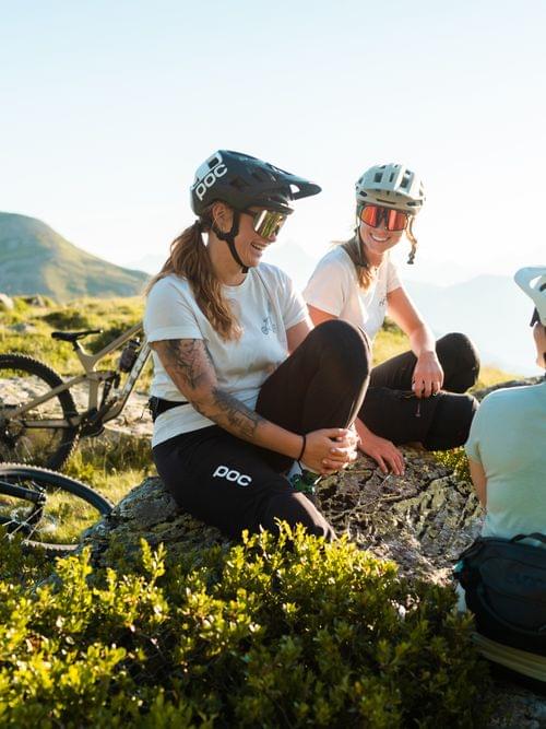 Group of women mountain bikers resting on a hilltop with bikes and scenic views