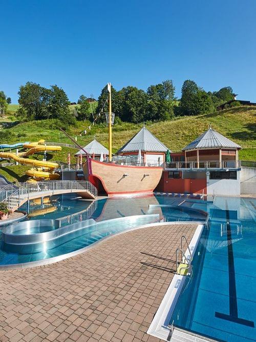 Outdoor water park with swimming pools, colorful water slides and a pirate ship play area