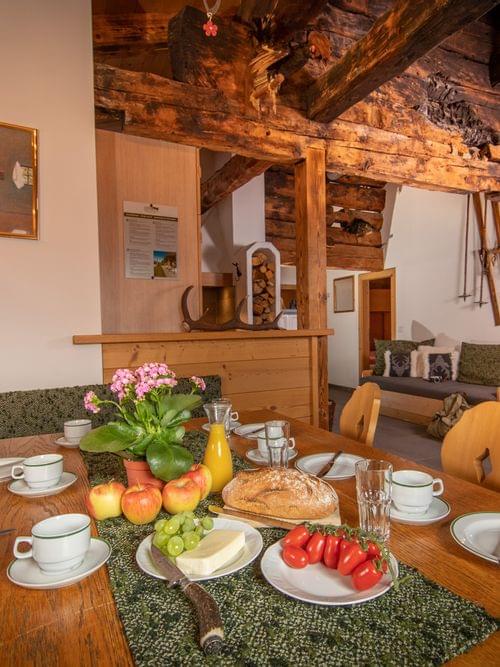 Rustic alpine dining room with wooden beams, set breakfast table, and cozy seating area