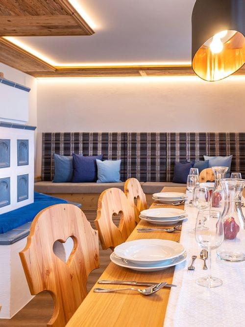 Gemütliches alpenländisches Esszimmer mit Holzmöbeln, gedecktem Tisch und Kachelofen