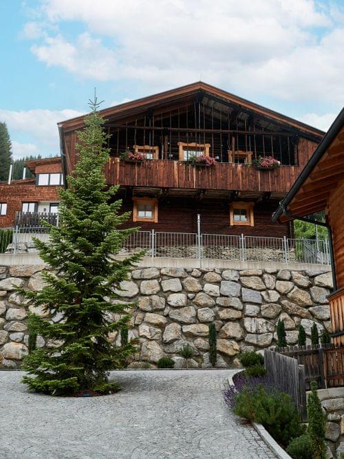 Alpine Holzhütten mit Steinmauern und Bäumen in einem Bergdorf