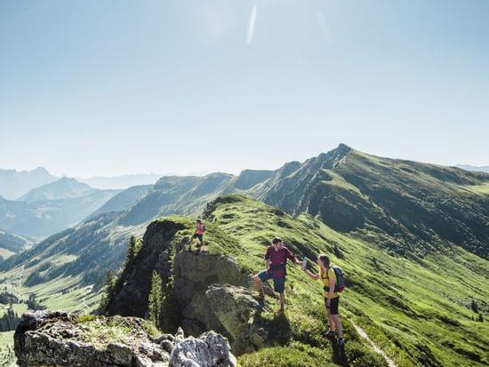 Wanderer auf felsigem Bergpfad bei strahlender Sonne in alpiner Landschaft
