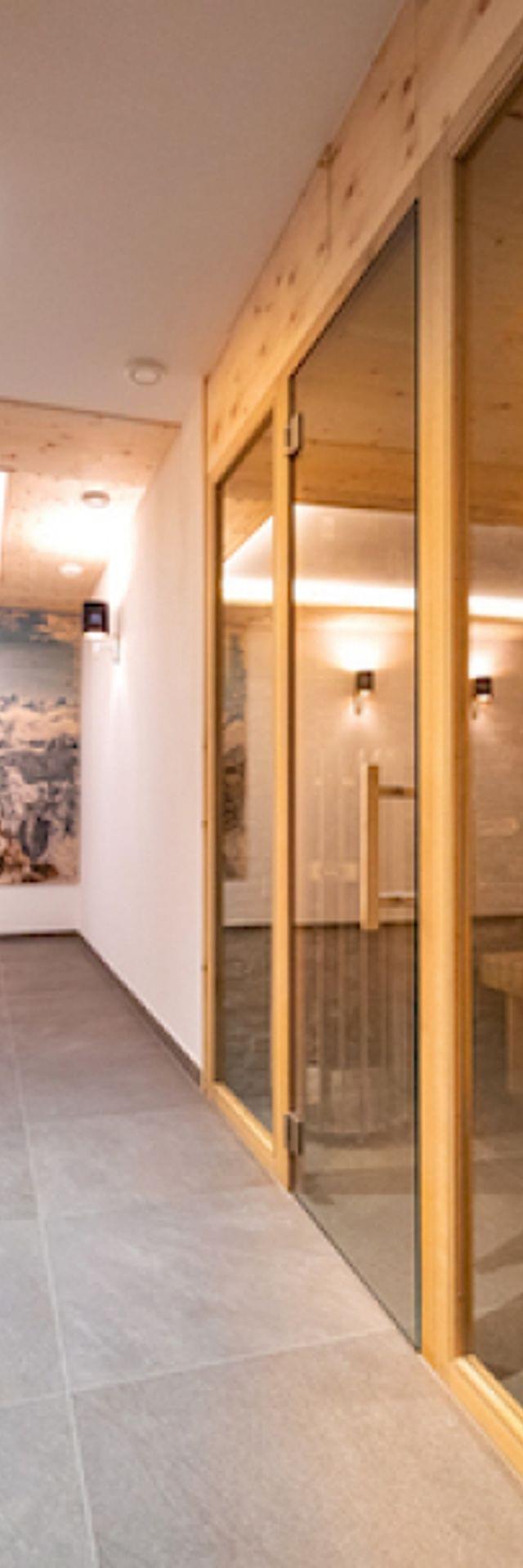 Moderner Wellnessbereich mit Holzsauna, gefliestem Boden und Wandkunst