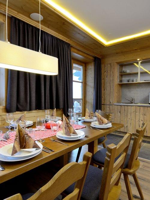 Rustic alpine kitchen and dining table set for dinner with wooden interior and mountain view