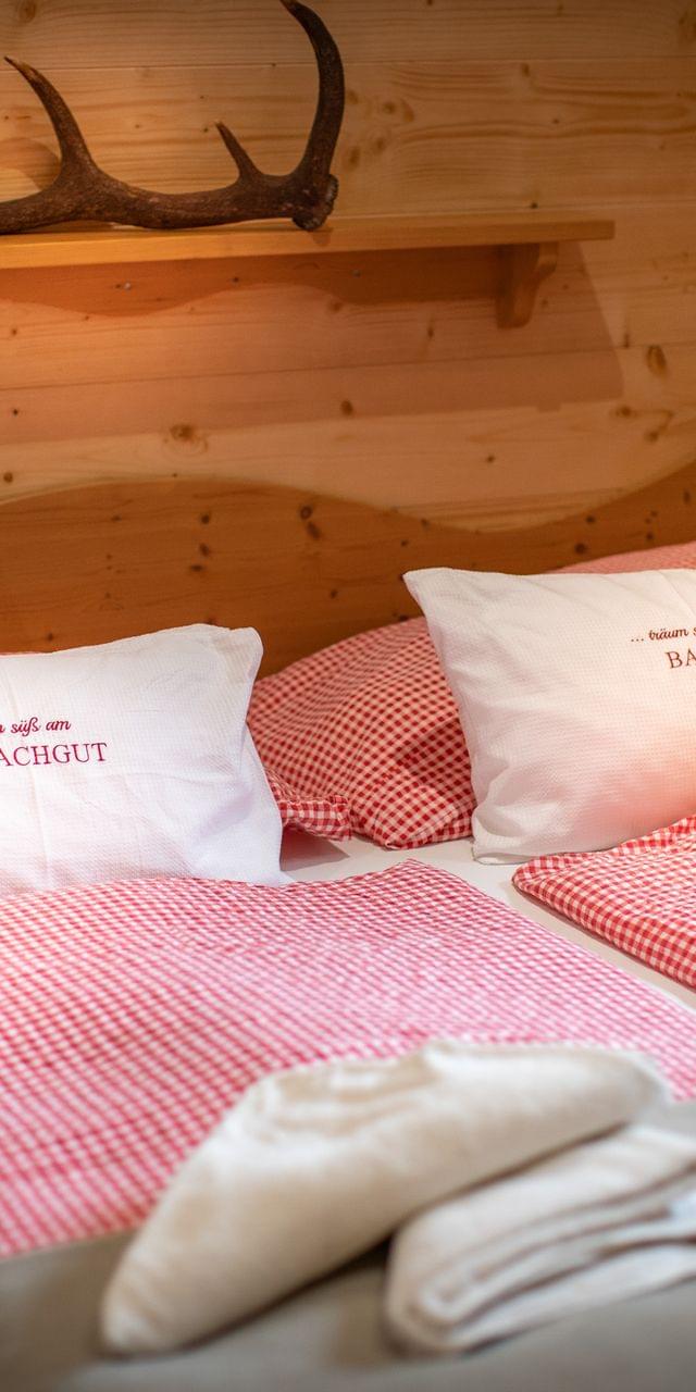 Gemütliches Alpenhotelzimmer mit rot kariertem Bettzeug und Holzverkleidung