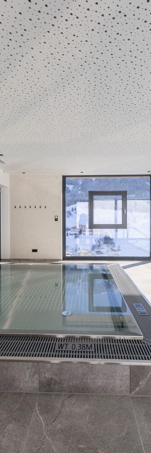 Badehaus Kinderbereich, Kinder-Wasserbecken mit Fischen an der Wand und Ausblick auf die Verschneite Bergwelt 