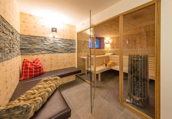 A large sauna with a glass front, with a cozy bench in front for relaxing.