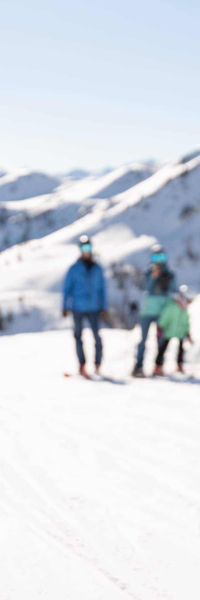 A child with their parents in the snow, holding a snowball.