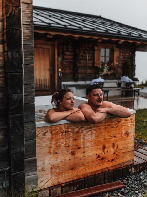 2 Personen in der Whirlwanne die im freien steht, sie genießen die Aussicht 