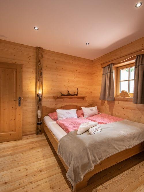 Gemütliches Alpen-Schlafzimmer mit Holzmöbeln und Doppelbett in rustikaler Berghütte