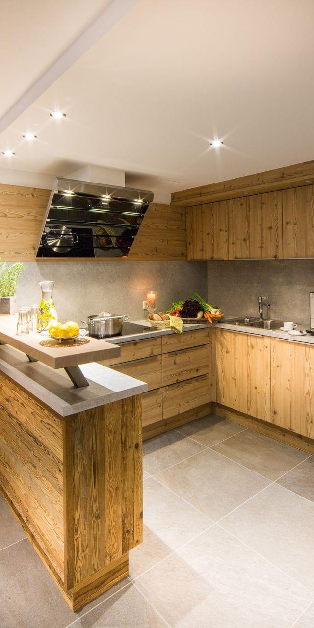 Moderne Holzküche mit Einbaugeräten, Kücheninsel und frischem Gemüse auf der Arbeitsplatte