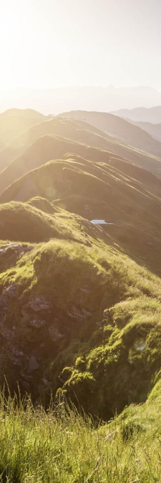 Wanderer auf sonnigem Bergrücken mit Panoramablick auf die Alpen
