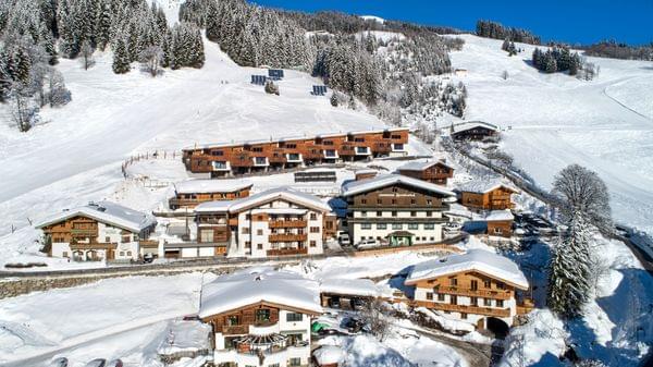 Alpines Skidorf mit Holzhütten und verschneiten Pisten im Winter