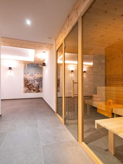 Moderner Wellnessbereich mit Holzsauna, gefliestem Boden und Wandkunst