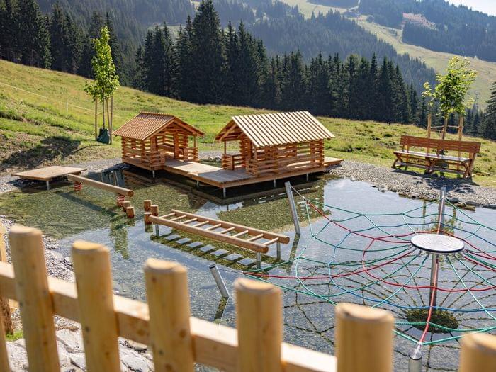 Holzspielplatz mit Kletternetz und Hütten in flachem Gebirgswasserpark