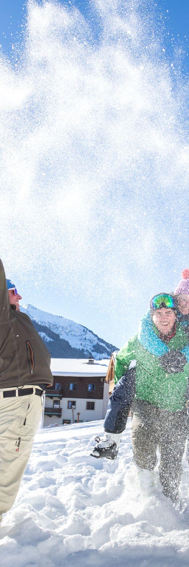 Freundesgruppe spielt im Schnee an einem sonnigen Wintertag im alpinen Skigebiet