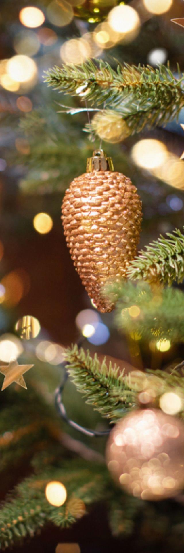 Weihnachtsbaum mit goldenen Kugeln, Tannenzapfen und Lichterkette geschmückt