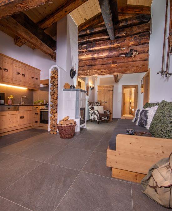 Gemütliches Alpen-Wohnzimmer mit rustikalen Holzmöbeln, kleiner Küche und Kamin