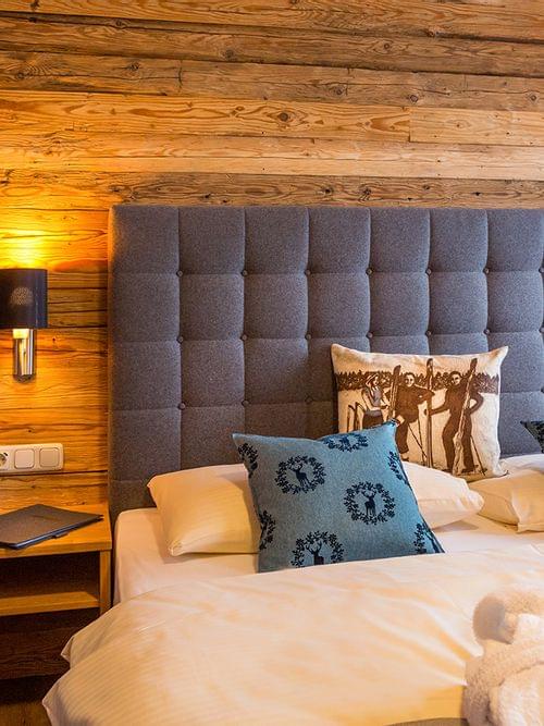 Cozy hotel room with wooden walls, double bed, blue cushions and warm lighting