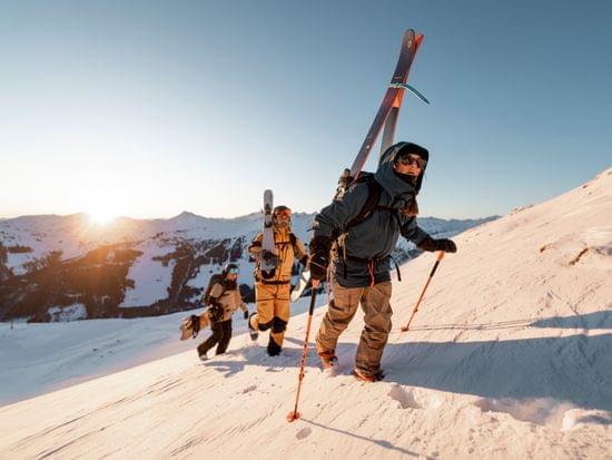 Group of backcountry skiers climbing snowy mountain slope at sunrise