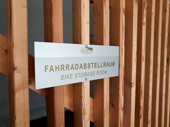 Bike storage room sign mounted on wooden slats at Bachgut resort