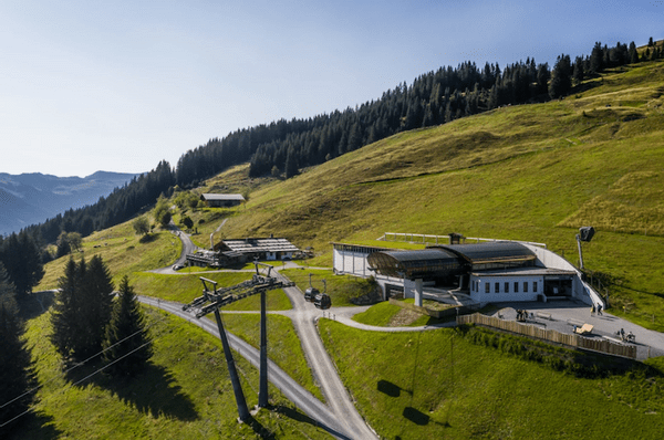 Bergbahnstation umgeben von grünen Hügeln und Wald im Sommer