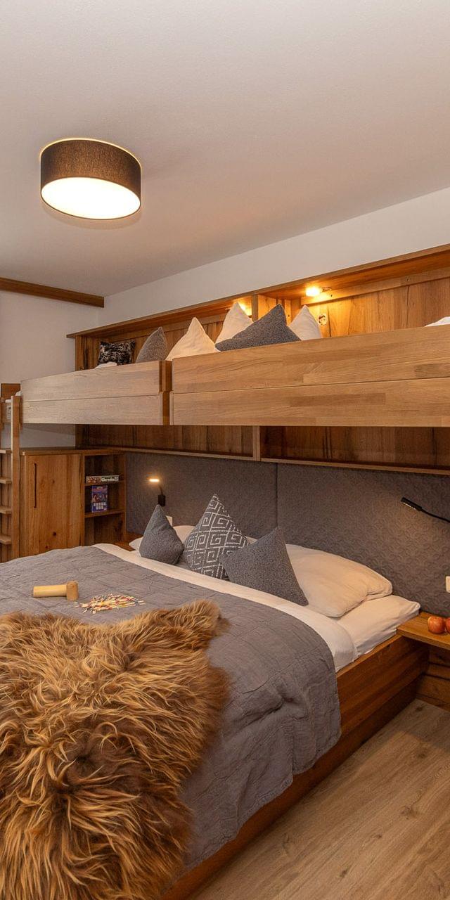 Cozy alpine hotel room with double bed and wooden bunk beds in winter setting