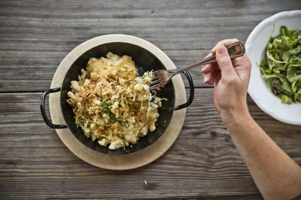 Käsespätzle mit Röstzwiebeln in einer Pfanne und Beilagensalat