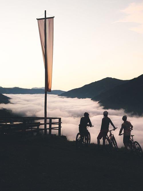 Radfahrer genießen den Sonnenaufgang über einem wolkenverhangenen Tal in den Bergen