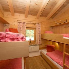 Cozy wooden cabin bedroom with bunk beds and red gingham bedding