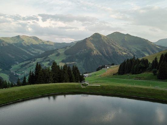 Berglandschaft in Österreich mit Alpensee, Wald und grünen Hügeln bei Sonnenuntergang