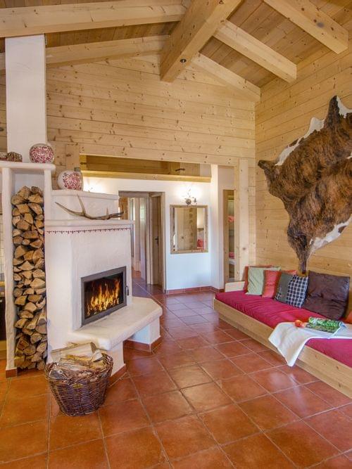 Gemütliches Chalet mit Holzwänden, Kamin, offener Küche und eingebautem Sofa mit bunten Kissen