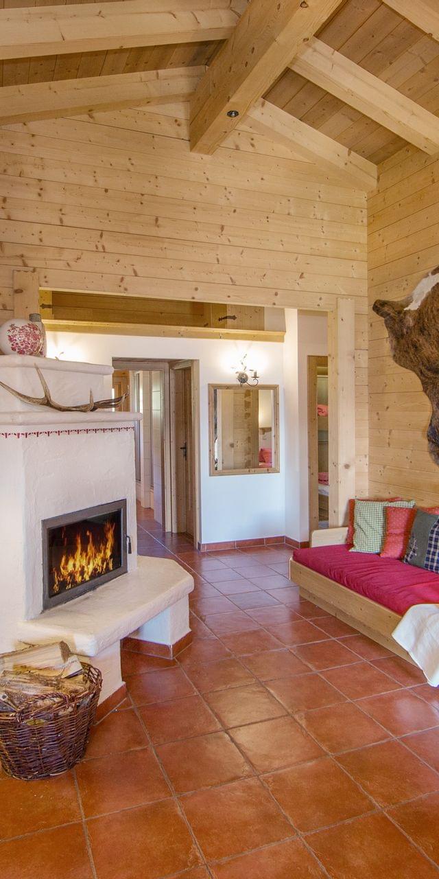 Gemütliches Chalet mit Holzwänden, Kamin, offener Küche und eingebautem Sofa mit bunten Kissen
