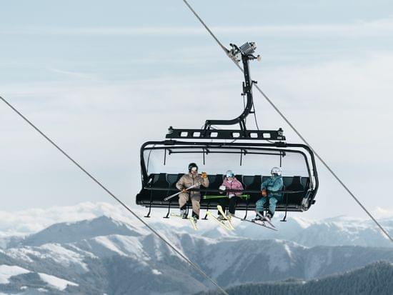 Sessellift mit 3 Personen darauf 