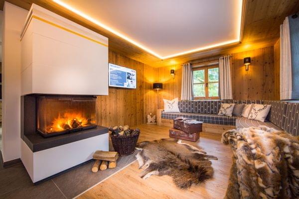 A cozy living room with a seating area and a fireplace, in an alpine-chic style with lots of wood.