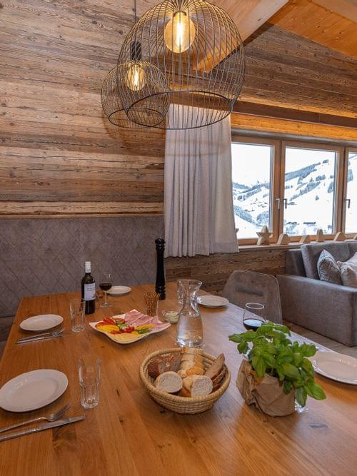 Gemütlicher Chalet-Essbereich mit Holzwänden, gedecktem Tisch und Bergblick durch große Fenster