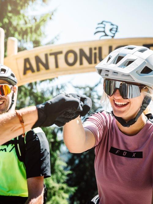 Mountain bikers smiling and fist bumping at the Antonius Trail entrance