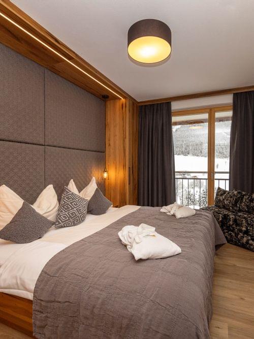 Modern hotel room with double bed, mountain view balcony and cozy lighting