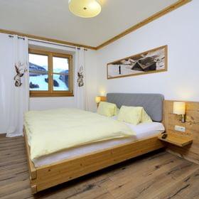 Cozy alpine hotel room with wooden furniture, double bed, and mountain view