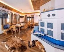 Gemütliches alpines Chalet-Esszimmer mit Holzmöbeln, Kachelofen und Fellteppich