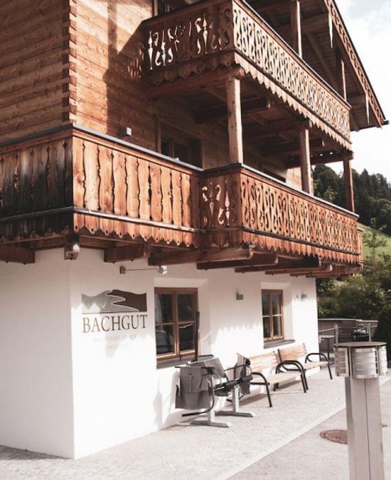 Traditional wooden alpine guesthouse with carved balcony and parked car in mountain setting