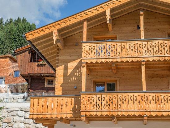Traditional alpine wooden chalet with decorative balconies in sunny mountain setting