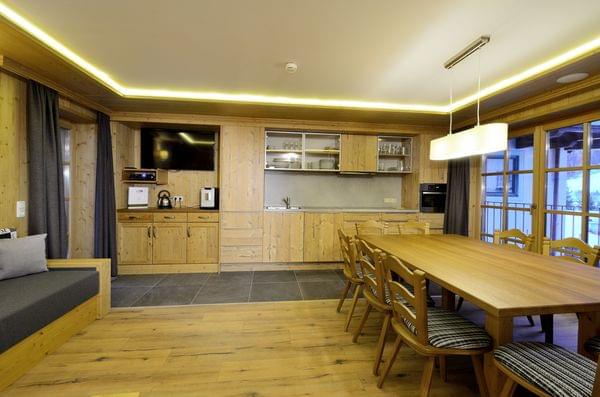 Modern alpine kitchen with wooden cabinets, long dining table, and built-in appliances