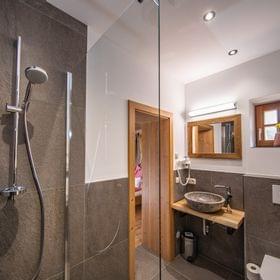 Modernes Badezimmer mit Steinwaschbecken, begehbarer Dusche und Holzakzenten