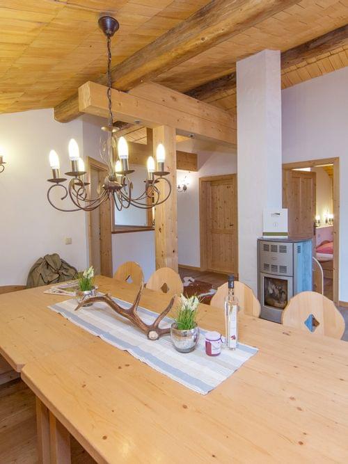 Gemütliches Esszimmer im Alpenstil mit Holzmöbeln, rustikalem Kronleuchter und Fernseher