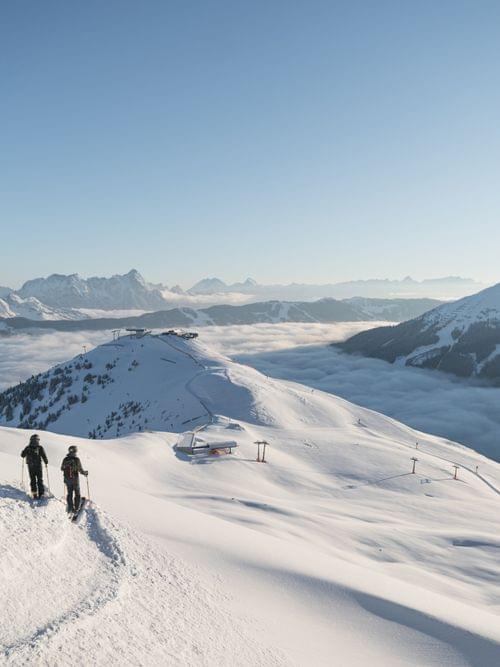 Skifahrer wandern durch frischen Schnee in alpiner Winterlandschaft mit Panoramablick