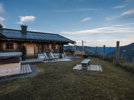 Bachalm im Sommer von außen, Whirlwanne, Bänke und Berge sind zu sehen. 